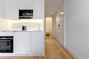 Una cocina moderna con armarios blancos, horno integrado y microondas.