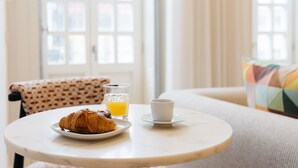 Ein Frühstückstisch mit einem Croissant auf einem Teller, einem Glas Orangensaft und einer Tasse.