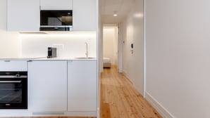A modern kitchen with white cabinetry, a built-in oven, and a coffee maker. - Feel Porto Cl Rigos Charm Flat 3 3 (Porto)