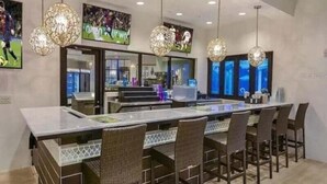 Una cocina moderna con una isla grande, asientos tipo bar, iluminación colgante y recuerdos deportivos en las paredes.