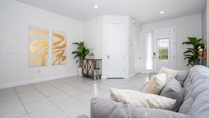 Ein geräumiges Wohnzimmer mit einem grauen Sofa, einem kleinen Beistelltisch und zwei großen, abstrakten goldenen Gemälden an der Wand.