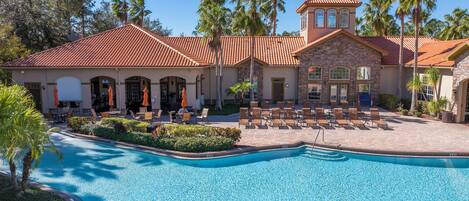 A resort with a swimming pool, outdoor seating, and palm trees.