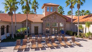 A building with a stone facade, multiple windows, and a tiled roof. There are outdoor chairs arranged in rows.