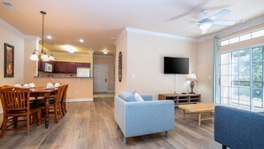 A spacious living room with a dining area, a sofa, and a television.