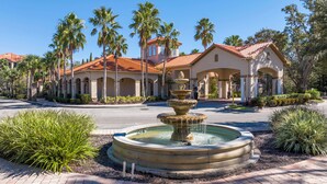 A resort with a central fountain, palm trees, and a building with a red-tiled roof.