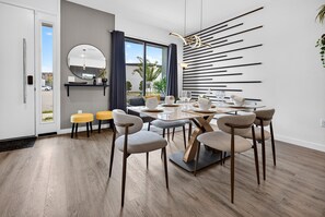 Un espace repas moderne avec une table ronde, plusieurs chaises et un élément décoratif mural.