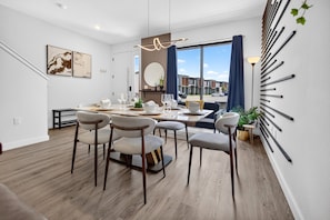 Une salle à manger moderne avec une grande table, plusieurs chaises et une vue sur l’extérieur.