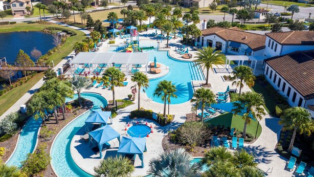 A resort with a large swimming pool, palm trees, and a water slide.