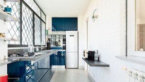 A modern kitchen with blue cabinets, a stainless steel refrigerator, and a gas stove.