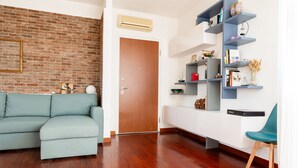 A living room with a brick wall, a wooden door, a light blue sofa, a white console table, and a blue chair.