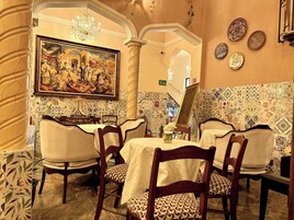 Un comedor con un cuadro grande, baldosas estampadas y una araña.