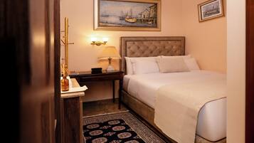 A hotel room with a bed, nightstand, lamp, and a painting on the wall.