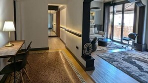 Una habitación de hotel moderna con comedor, un ventanal grande y un pilar decorativo.
