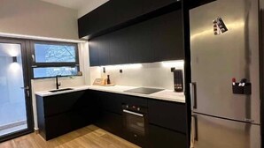 Una cocina moderna con gabinetes negros, un refrigerador de acero inoxidable y un lavavajillas integrado.