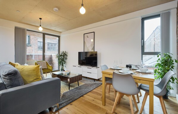 Una sala de estar moderna con sofá, mesa de centro y comedor con sillas y mesa.
