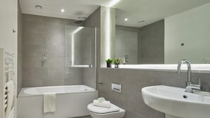 A modern bathroom with a bathtub, toilet, and sink. - Stylish Northern Quarter Sanctuary (Manchester)
