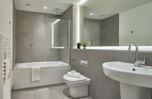 A modern bathroom with a bathtub, toilet, and sink. - Stylish Northern Quarter Sanctuary (Manchester)