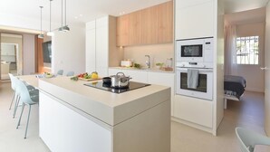 A modern kitchen with a central island, built-in oven, microwave, and a dining area with chairs.