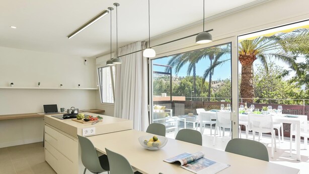 A modern kitchen with a large island, white cabinetry, and a dining area with a table and chairs.