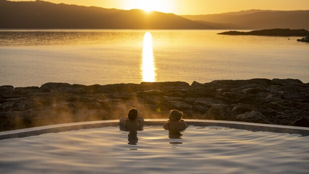 A couple in an infinity pool with a sunset view.