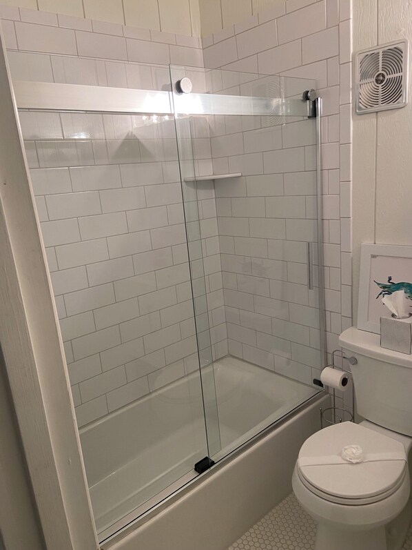 A bathroom with a glass-enclosed shower, a toilet, and a white tiled wall. - Town of Bethany Beach- one block from beach (Bethany Beach)
