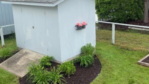 A small, white shed with a metal roof, surrounded by a grassy yard and a white fence. - Town of Bethany Beach- one block from beach (Bethany Beach)