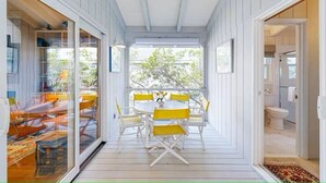 A covered outdoor dining area with a table and chairs, a view of the outdoors, and a door leading to a bathroom. - Town of Bethany Beach- one block from beach (Bethany Beach)
