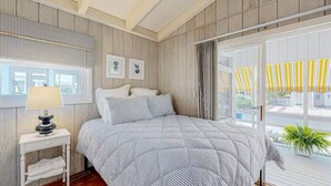 A bedroom with a bed, a nightstand, a window with blinds, and a view of the outside. - Town of Bethany Beach- one block from beach (Bethany Beach)