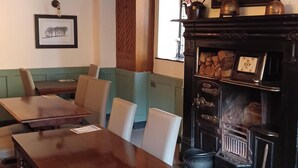 A restaurant interior with a wooden table and chairs, a menu board, and a fireplace. - George Hotel Hayfield (High Peak)