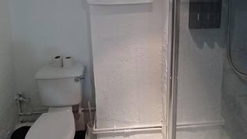 Un baño pequeño con inodoro, cabina de ducha y una toalla colgada en la pared.
