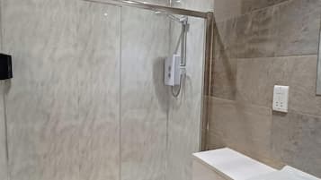 Un baño moderno con ducha de vidrio, inodoro blanco y tocador con lavamanos.
