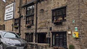 A stone building with a sign reading "GEORGE HOTEL" and a car parked in front. - George Hotel Hayfield (High Peak)