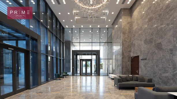 A spacious lobby with a modern design, featuring a large chandelier, a seating area with sofas, and a glass entrance. - Prime Select Mall of Arabia (6th of October City)