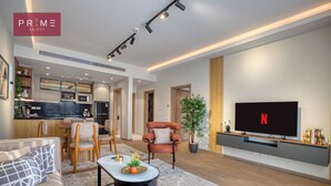 A modern living room with a sofa, coffee table, TV, and a kitchen area in the background. - Prime Select Mall of Arabia (6th of October City)