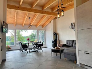 A modern kitchen with a dining area, large windows, and a fireplace. - Ferienwohnung mit Eigenem Seezugang mit Steg (Warin)