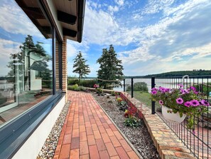A pathway leading to a lakeside view with a wooden deck and potted plants. - Holiday Apartment With Private Lake Access and Jetty (Warin)