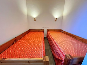 A twin room with two single beds, each with a wooden frame and a patterned bedspread.