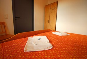 A room with a bed, a wooden wardrobe, and a door. - Holiday Apartment With Private Lake Access and Jetty (Warin)