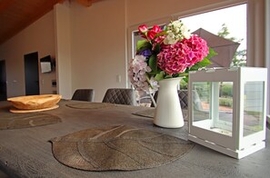 Une table à manger ornée d’un vase de fleurs, de sets de table et d’une lanterne blanche.