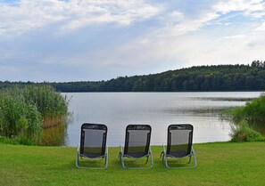 Three outdoor chairs facing a lake with a forested hill in the background. - Holiday Apartment With Private Lake Access and Jetty (Warin)