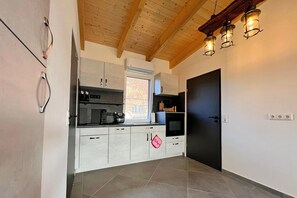 A kitchen with a wooden ceiling, a window, and a door. - Holiday Apartment With Private Lake Access and Jetty (Warin)