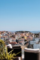 A rooftop terrace with a view of a cityscape, including buildings and a distant hill.