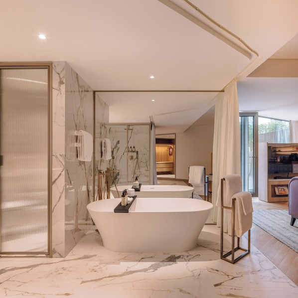 Une salle de bain moderne avec une baignoire sur pieds, un revêtement de sol en marbre et un grand miroir.