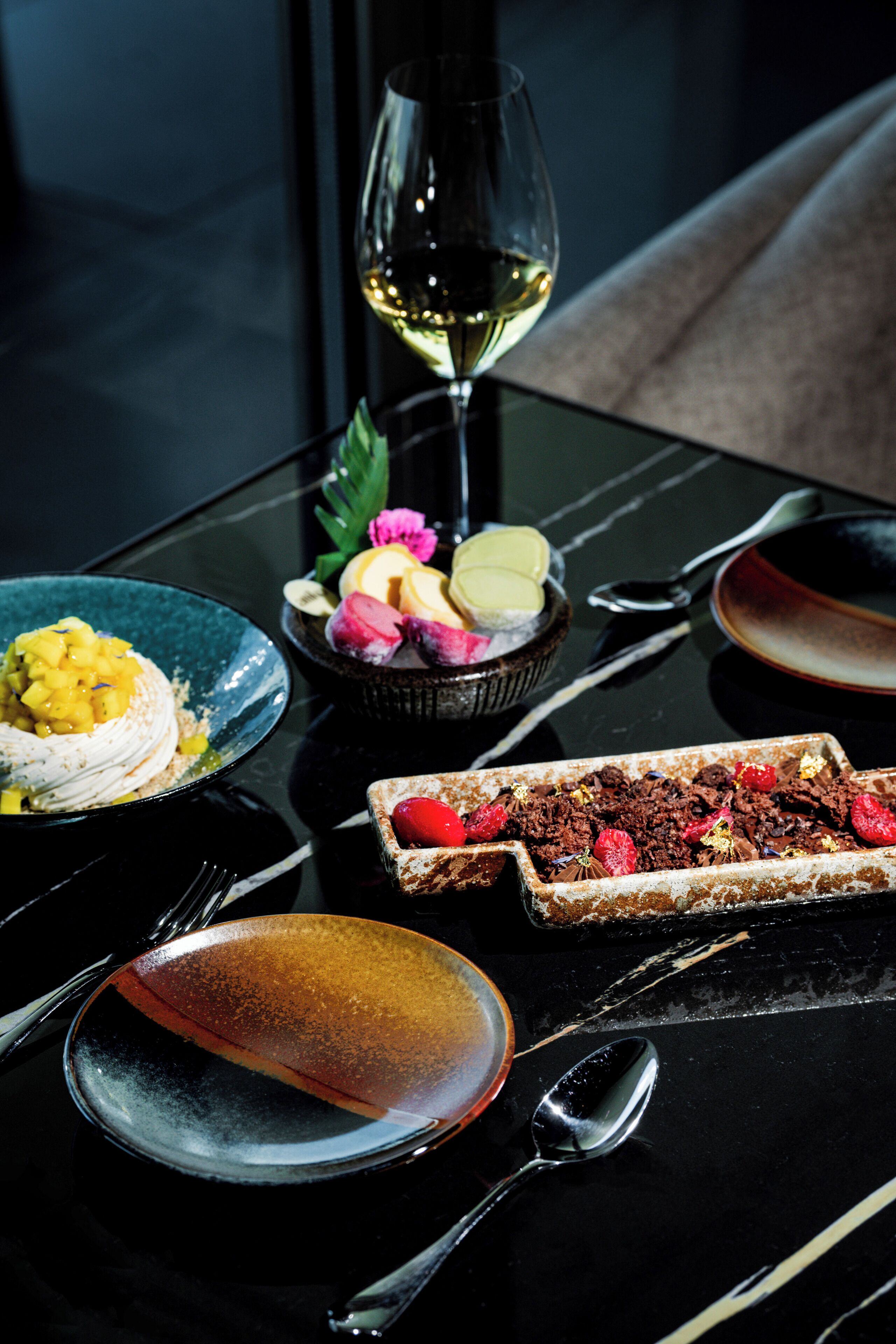 Une table avec divers desserts, un verre à vin et des couverts.