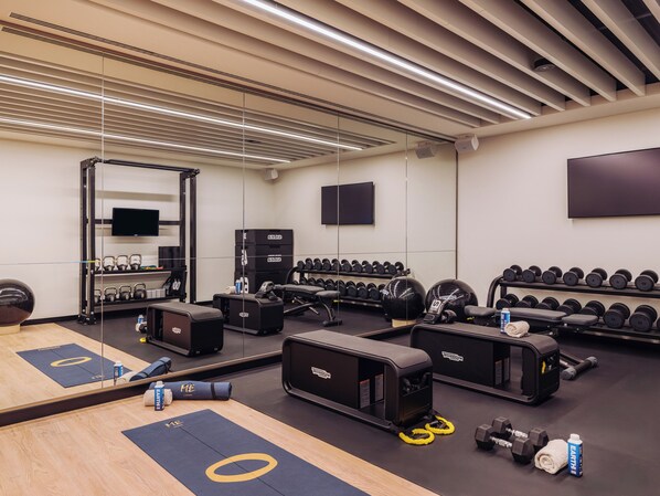 Une salle de sport moderne avec des murs recouverts de miroirs, des supports pour les poids et du matériel d'exercice.