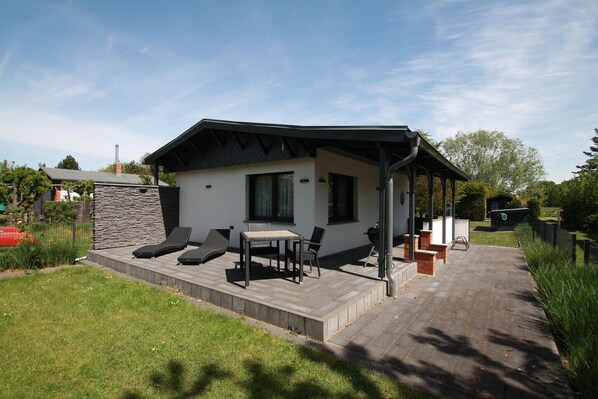Ein modernes Haus mit Terrasse, Grillplatz und einer Steinmauer.