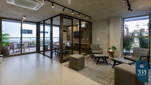 A modern office space with glass partitions, comfortable seating, and a view of the outdoors. - 2 Bedroom Apartment with Sea View Rooftop (Salvador)