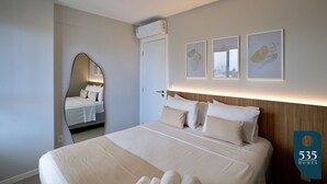A modern hotel room with a large bed, a mirror, and three framed artworks on the wall. - 2 Bedroom Apartment with Sea View Rooftop (Salvador)