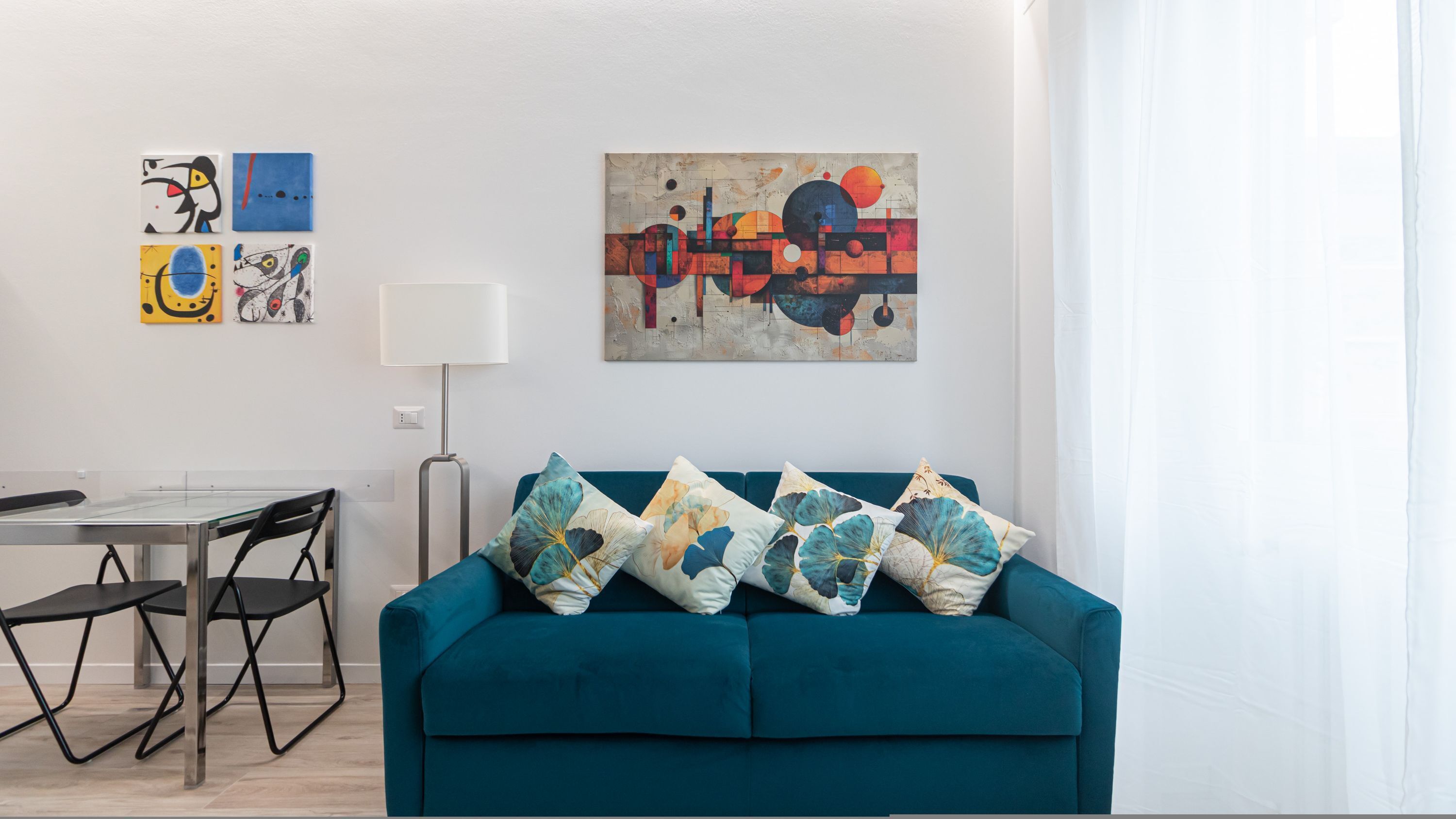 Una sala de estar moderna con un sofá color turquesa, una mesa de comedor de vidrio y una lámpara.