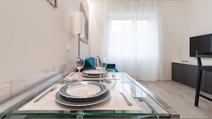 A modern dining area with a glass table set for two, featuring plates and cutlery. - Italianway - Serra 16 (Milan)